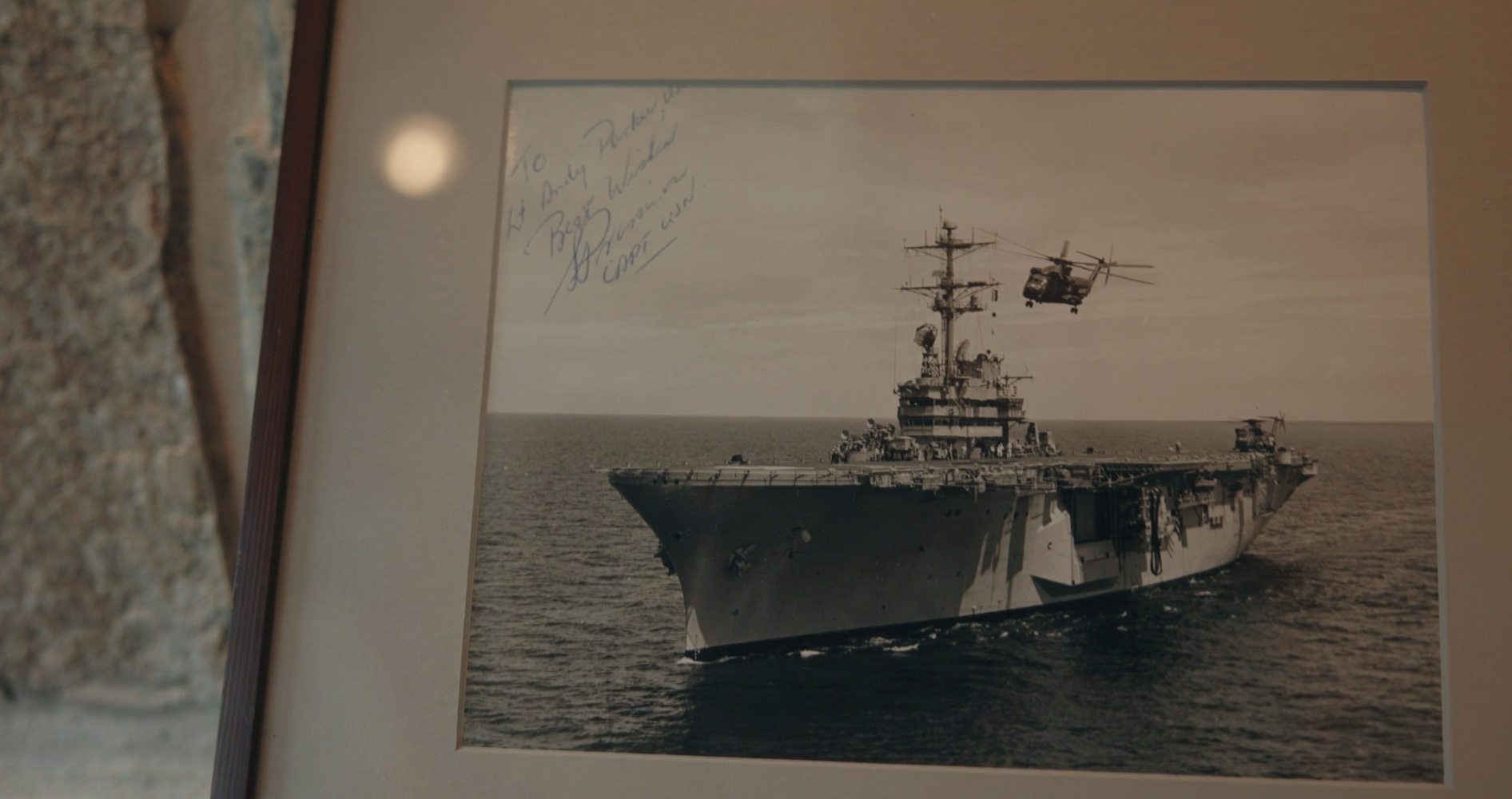 Signed photograph of a Navy carrier with a helicopter overhead